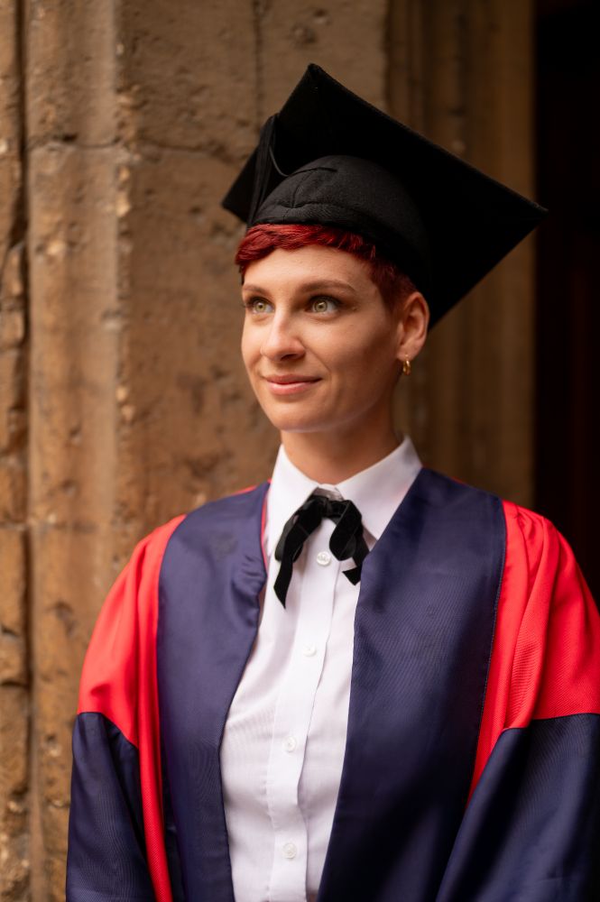 A woman in a red and blue DPhil gown