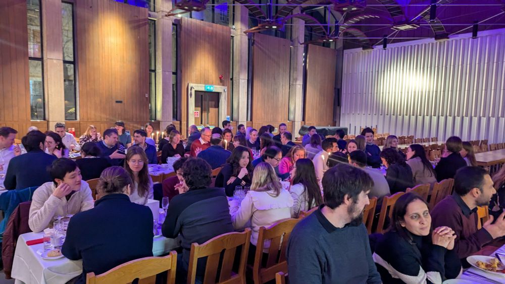 A large group of academics eating dinner together in an Oxford Hall.