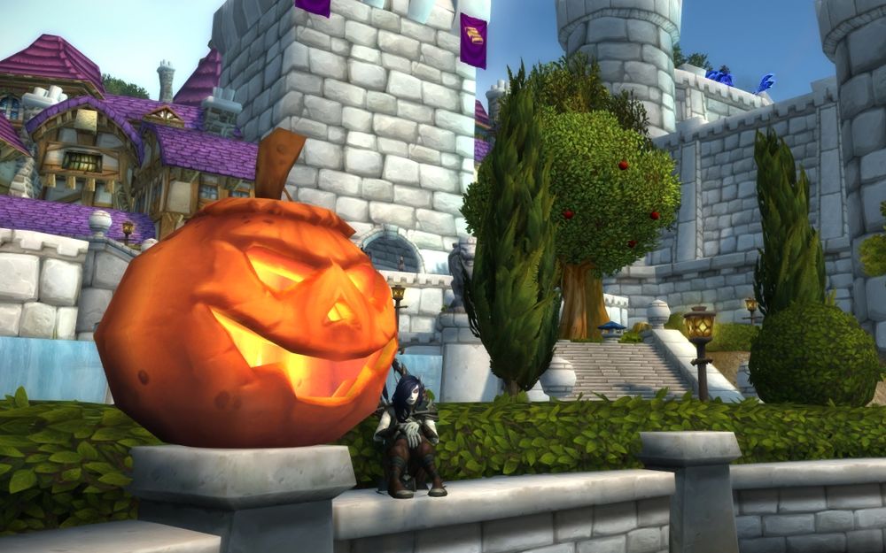 A screenshot from the game World of Warcraft. The player character is a dark ranger void elf with pointy ears, decaying skin, and long black hair. She is sitting next to a large jack-o-lantern in Stormwind's garden. 