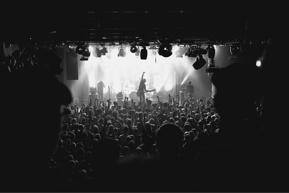 Konzertfoto der Band ITCHY. Im Vordergrund das Publikum, im Hintergrund die Band auf der Bühne.