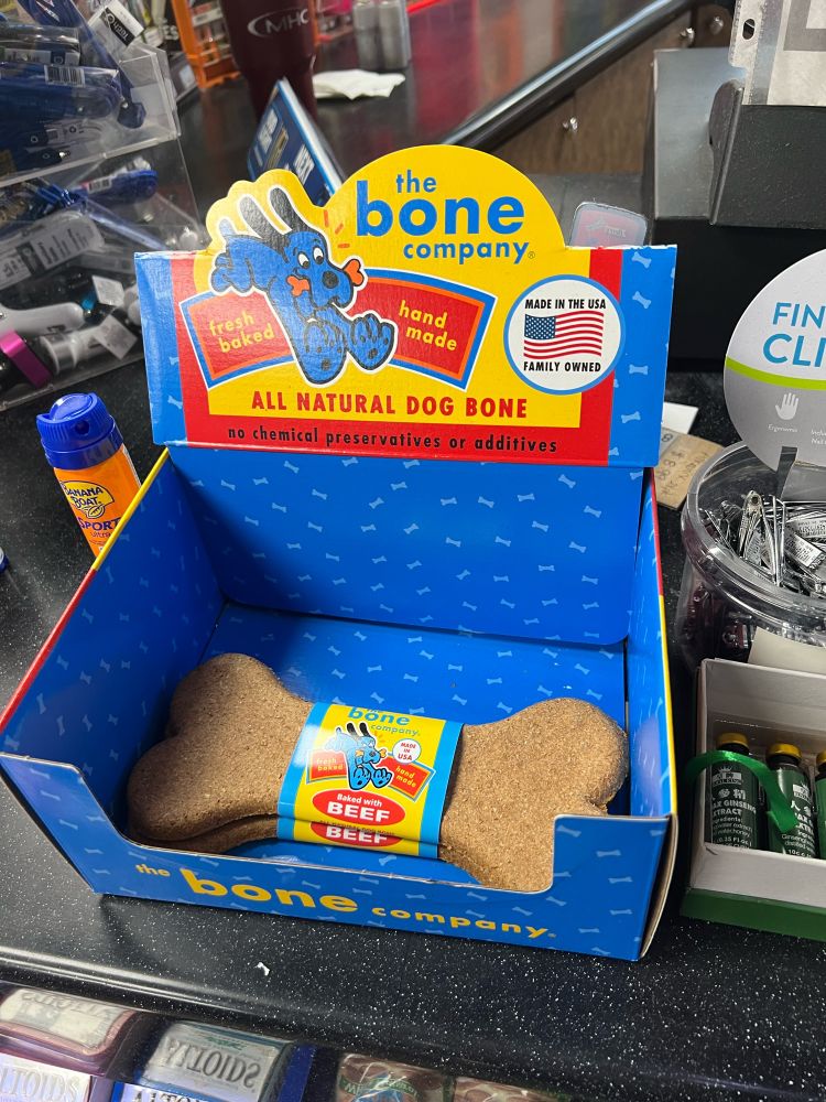 A box of “the bone company” all natural dog bone dog treats on a gas station counter