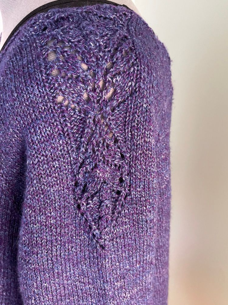 A close up of the lace detail on the shoulder of a blue-purple sweater