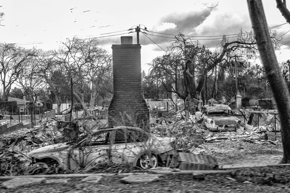Black and white photo of a burned out car after the Eaton Fire in Altadena.