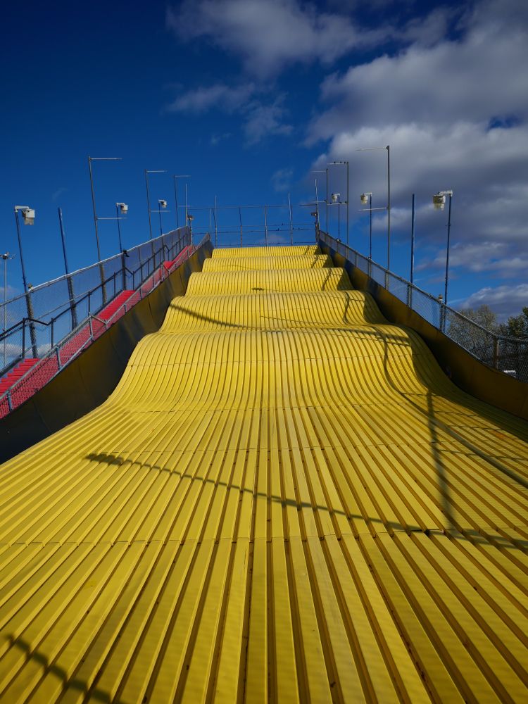 a multiple story metal county fair slide in the off-season, very yellow but very cold.