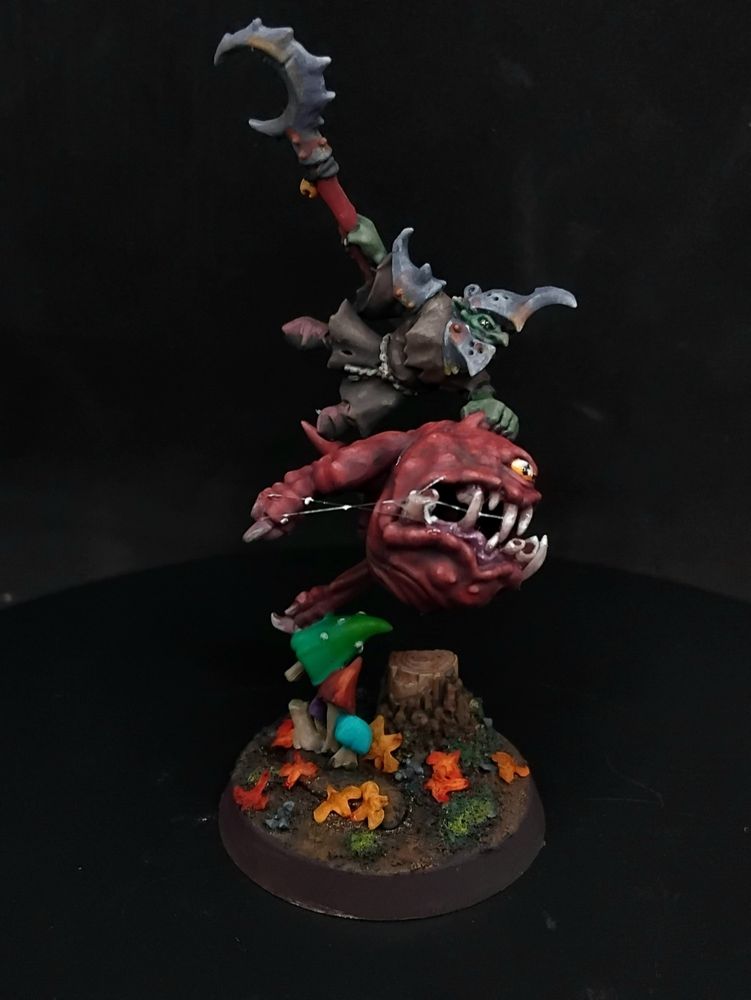 Goblin holding a sickle and holding onto a squig for dear life!