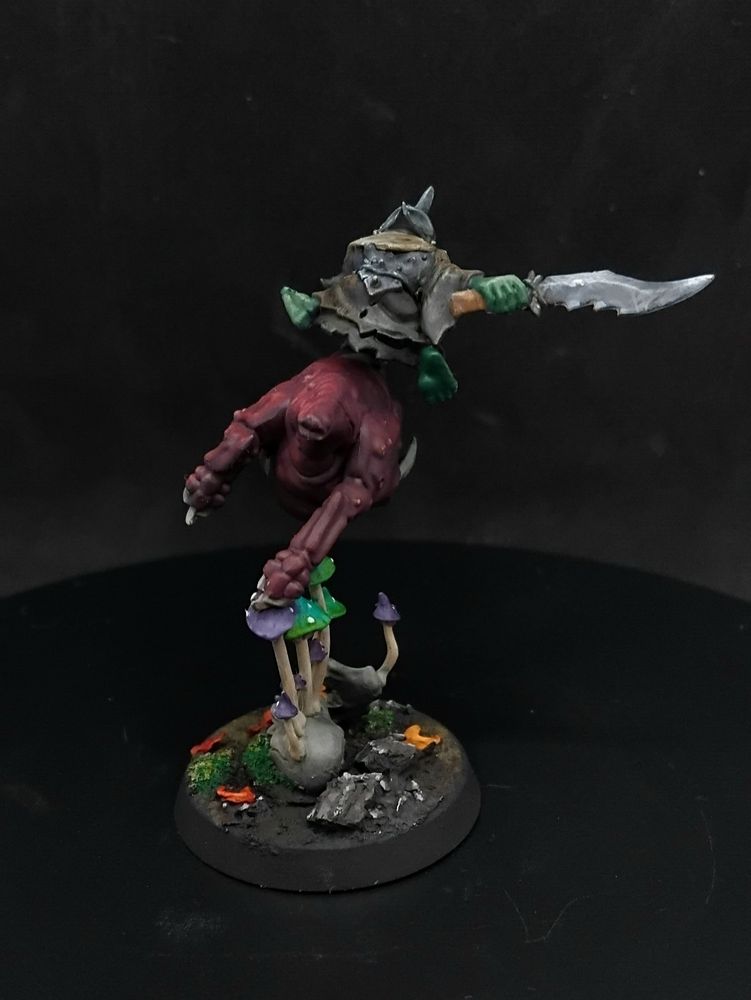 Goblin in a helmet and robes holding a sword riding a squig 