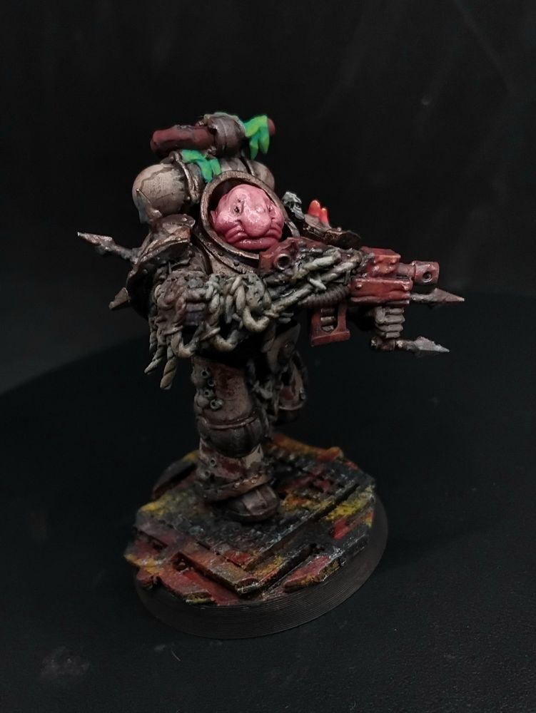 A figure in cream and brass nautical themed power armor holding a machine gun, their head is a blobfish and they have pink coral coming out of their shoulder