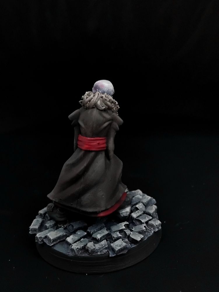 A bald vampire in a dark brown coat with a fur collar and red robe