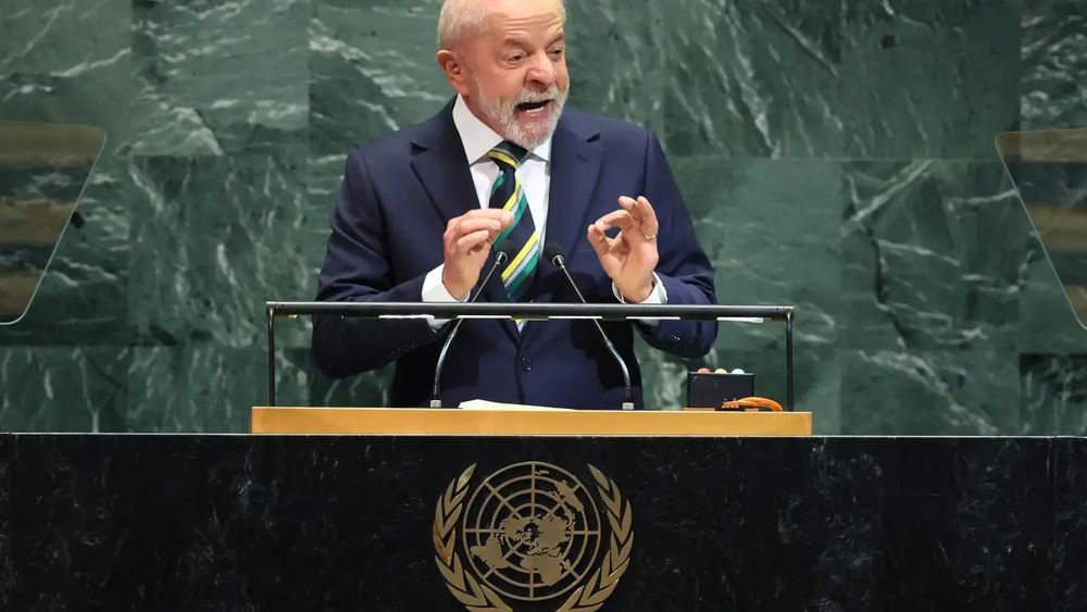 Lula discursando na Assembléia Geral da ONU, vestindo um terno azul escuro e gravata listrada, azul escuro, verde e amarela.  