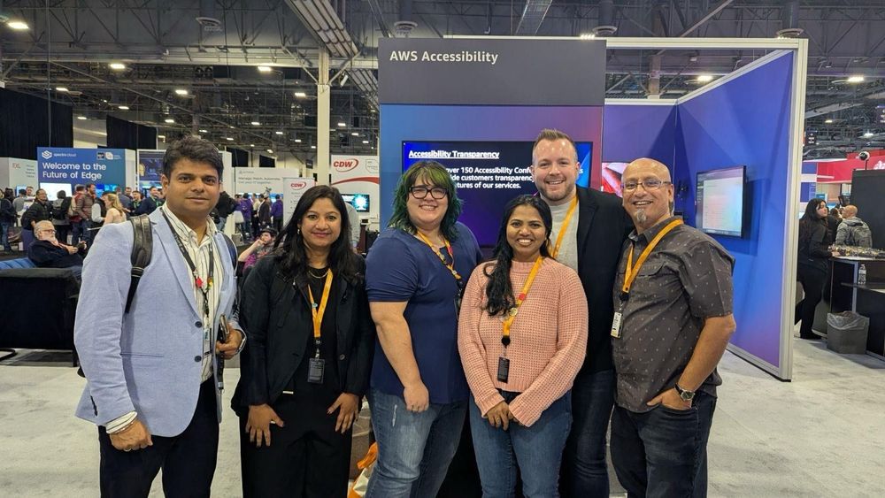 Group of people including Rick Suttles in front of a booth labeled AWS Accessibility. 