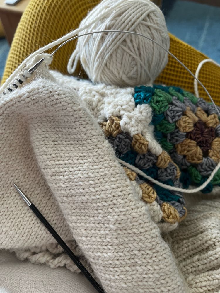 A partially completed sweater in mostly cream coloured alpaca is laying on a yellow waffle cotton-clad lap. A circular knitting needle is in play for a sleeve, with the yarn ball looking woefully small for the task. The knitter (whose lap it is and whose sweater it will be) is hopeful. Perhaps delusionally so. The sweater pattern is from Tanis Fibre Arts and the pattern is called Fleetwood. It is made using yarn from Blue Sky Fibre (cream alpaca/merino) and Crazy About Yarn Amun-Ra mini set for the crocheted front panel. 