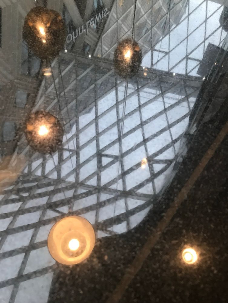 A reflection of lights and a ceiling made up of many panes of square glass, the words JOHN LEWIS upside down in the reflection. 
