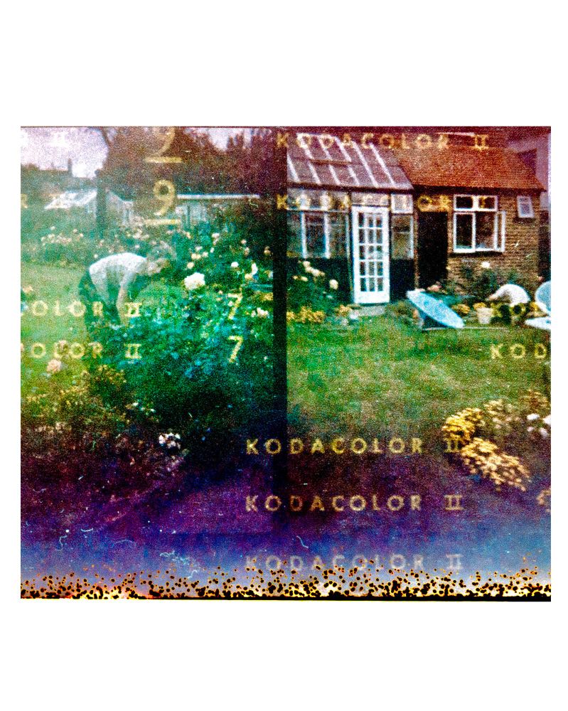 Very grainy film photo of a garden with space age furniture and a woman gardening, embossed with the words kodacolor II from the paper backing of the expired film roll circe 1970s 