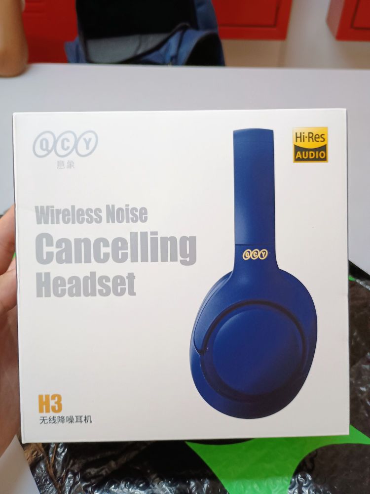 Na foto, mostra a caixa do fone de ouvido QCY H3, escrito "Wireless Noise Cancelling Headset", e um selo de Hi-Res Audio no canto superior direito.