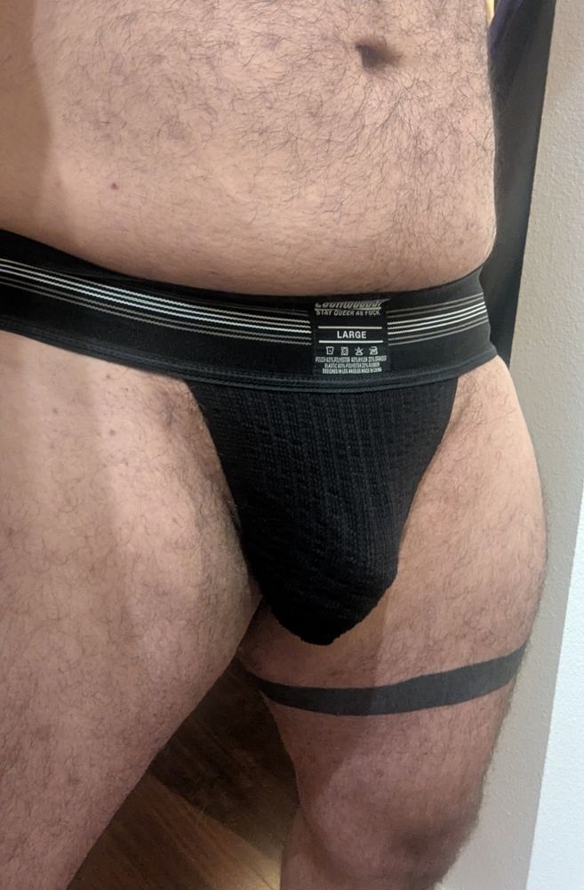 Navel to knees shot showing off my black wide band jockstrap. I've got a black band tattooed around my thigh on one leg and a bit of a dad bod.