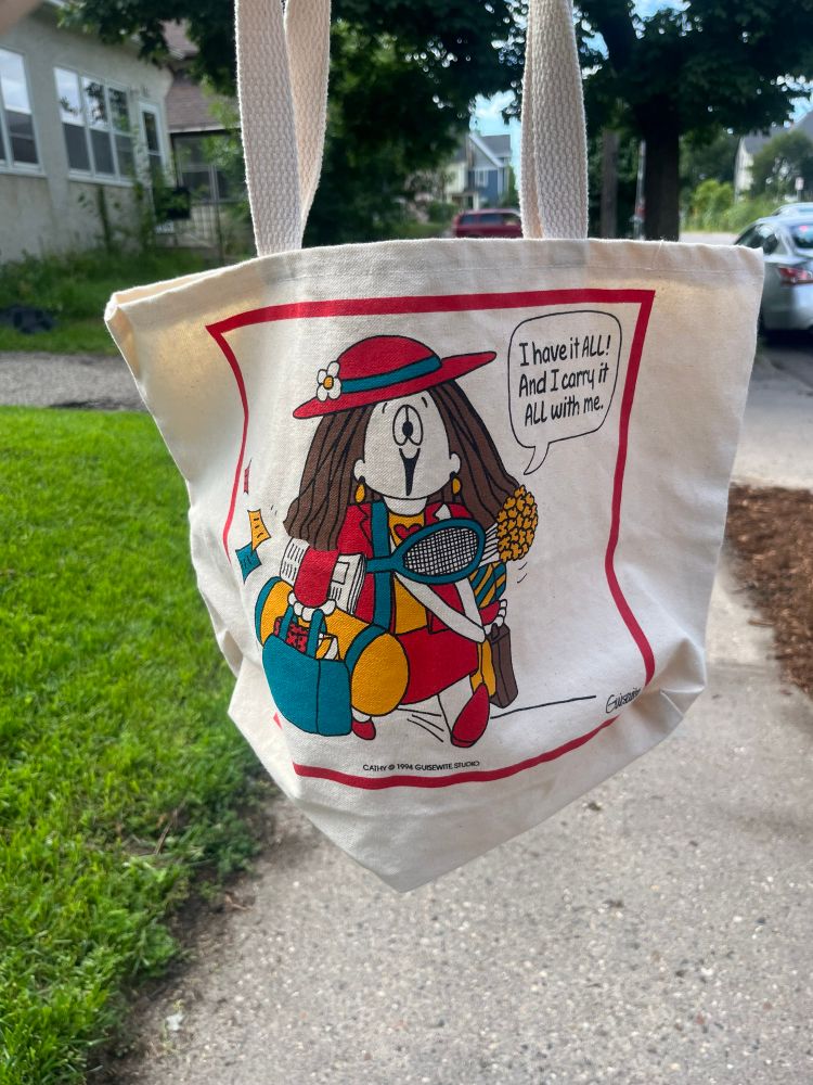 Cathy comic bag that says “I have it ALL! And I carry it ALL with me” with an image of Cathy carrying a bunch of miscellaneous items