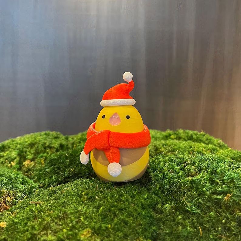 A photograph of a 3D-printed great serpent of Ronka wearing a little red, white-trimmed santa hat and matching red scarf with white pompoms.