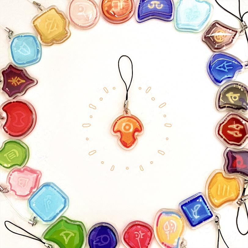 A photograph of a ring of kawaii-style small acrylic charms of the Soul Crystals from FFXIV, with one Azem crystal in the center of the ring. 