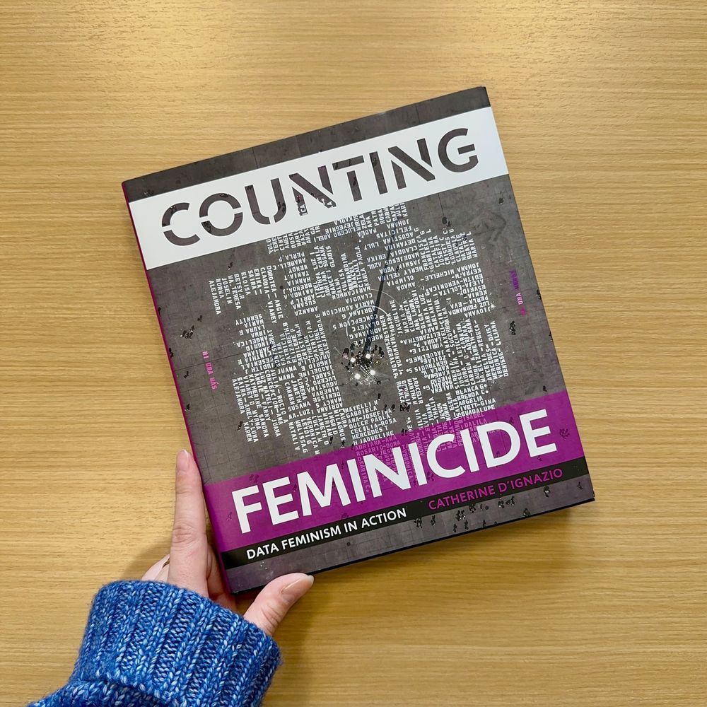 A copy of "Counting Feminicide: Data Feminism in Action" on a wood background.