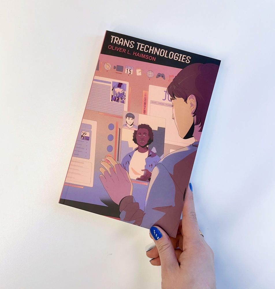 Hand holding a copy of "Trans Technologies" by Oliver L. Haimson. An illustrated cover depicts a person interacting with a digital interface.
