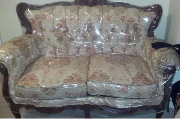 A 1980's two-cushioned chesterfield wrapped in plastic. 