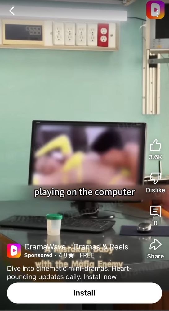 A computer with a blurred image of a porno on the screen. A semen collection jar sits in front of it 