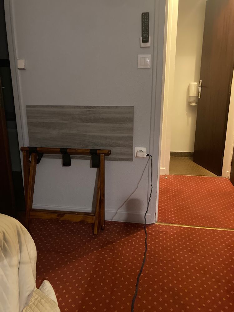 Chambre d’hôtel où la prise est au milieu d’un mur loin du bureau et loin du lit