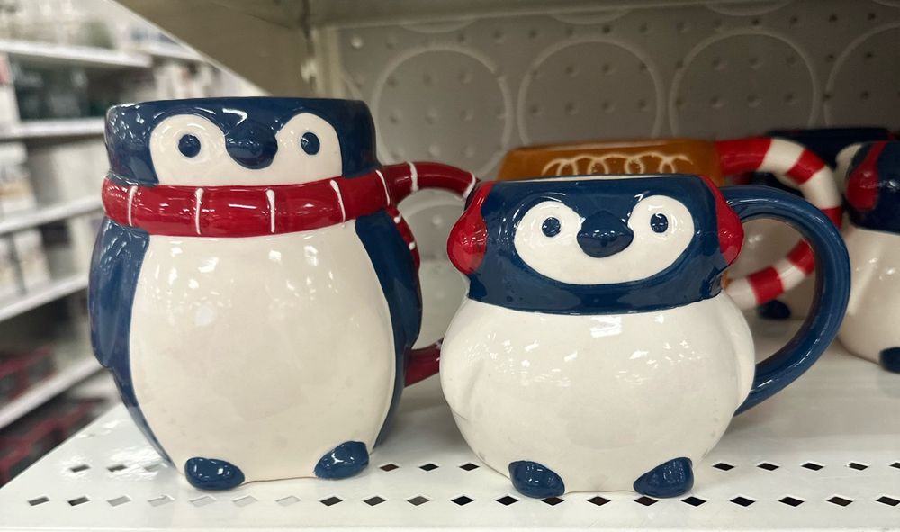 two penguin mugs, one is bigger with a scarf one is smaller with earmuffs