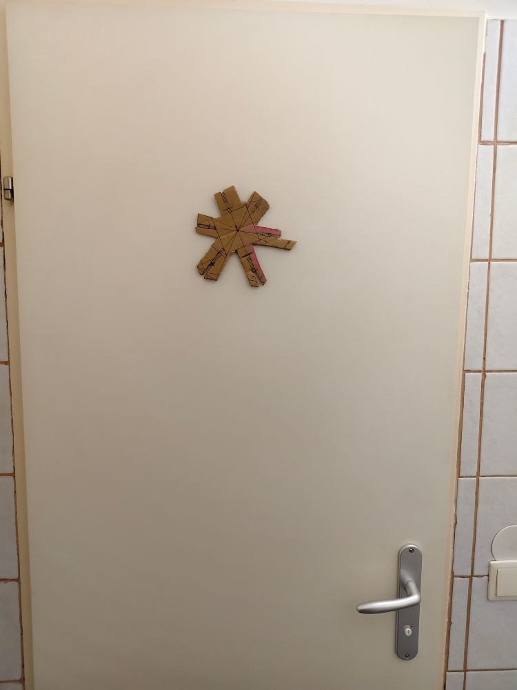 Ein irgendwie aus Karton gebastelter Stern auf einer tür