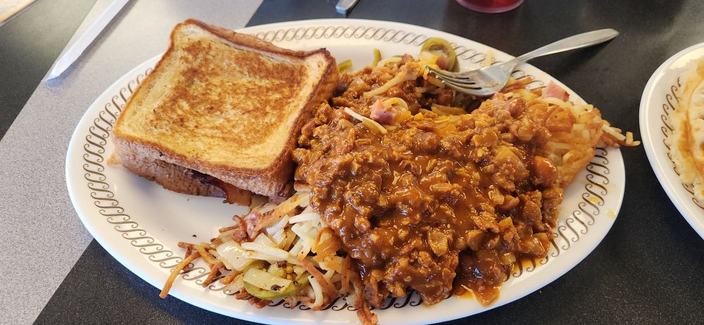 A bacon patty melt accompanied with a massive pile of scattered, smothered, covered, chucked, peppered, and topped hash browns.
