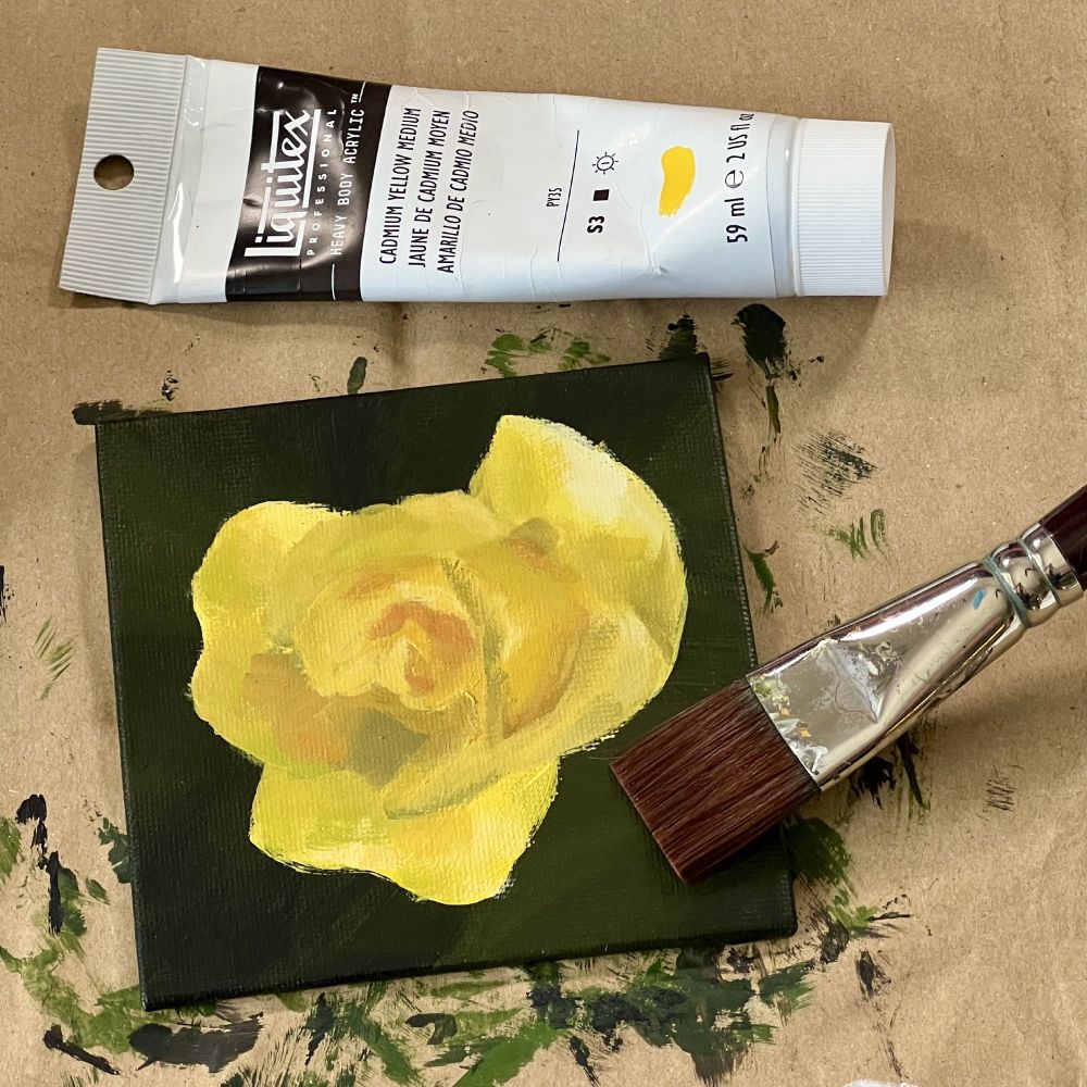 Small painting of a yellow rose flower. With a brush and a paint tube next to it