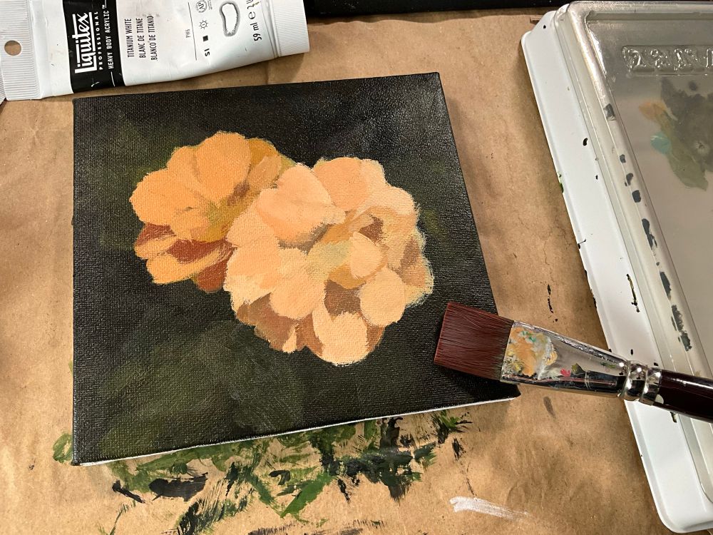 photo of an in progress flower painting on a canvas with a brush on it.