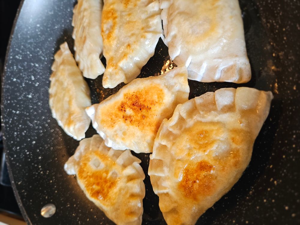 Homemade pierogis getting sautéed in Irish butter in a skillet. 