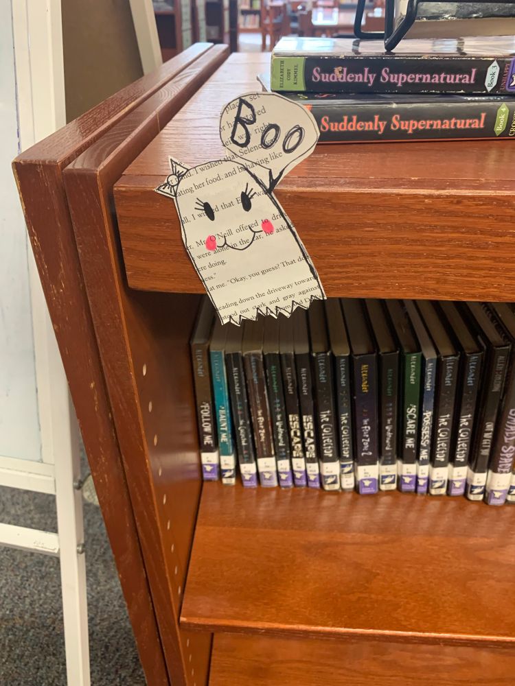 Ghost made from a book page on a bookshelf. 