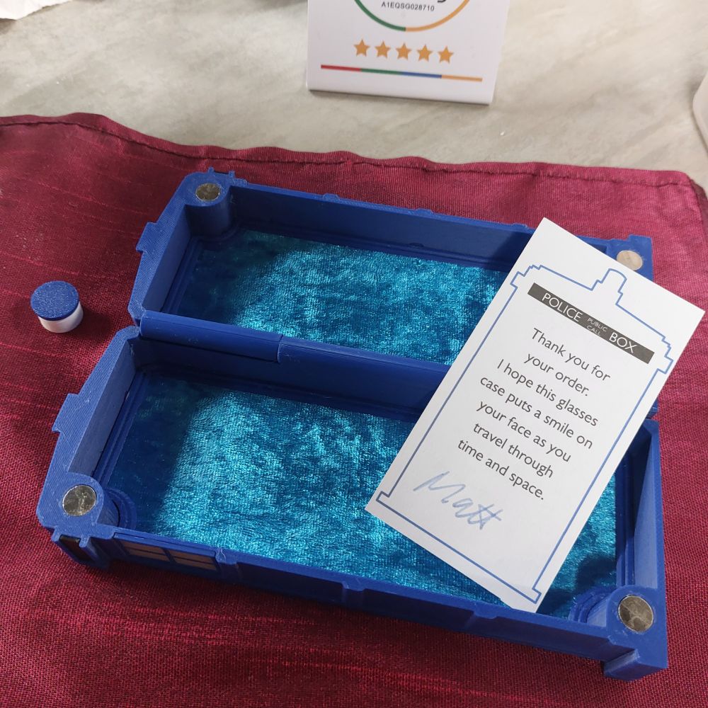 Open Tardis shaped glasses case with blue velvet linen and business card inside