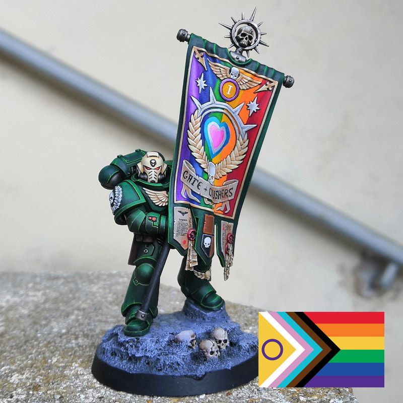 Dark Angle space marine holding a flag painted in the colors of the progress flag.
