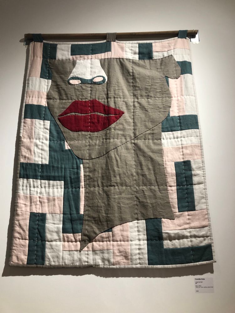 Textile artwork depicting the lower half of a woman’s face