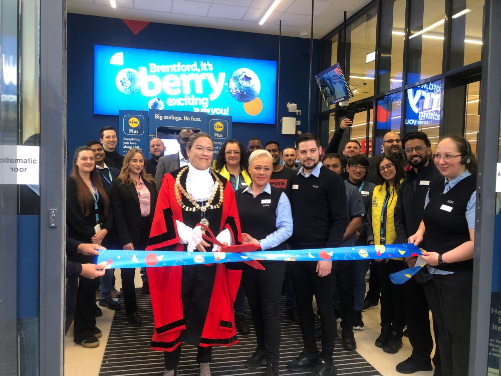 Mayor Amy Croft cutting the ribbon in front of the store with staff 