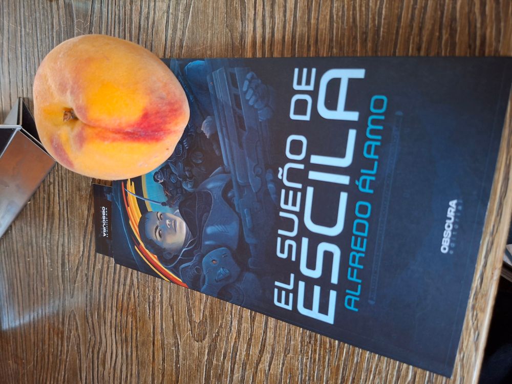 En una mesa el libro de El sueño de escila y un melocotón 