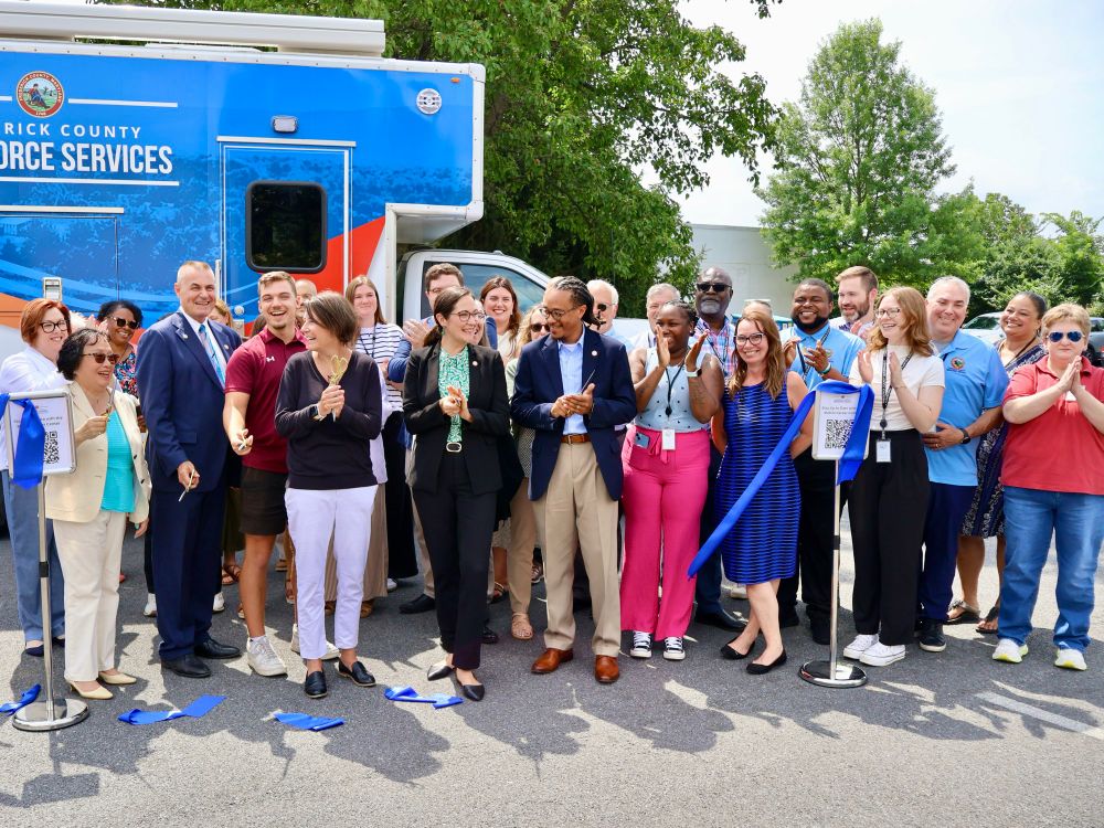 An image of a group of people outdoors smiling and clapping.