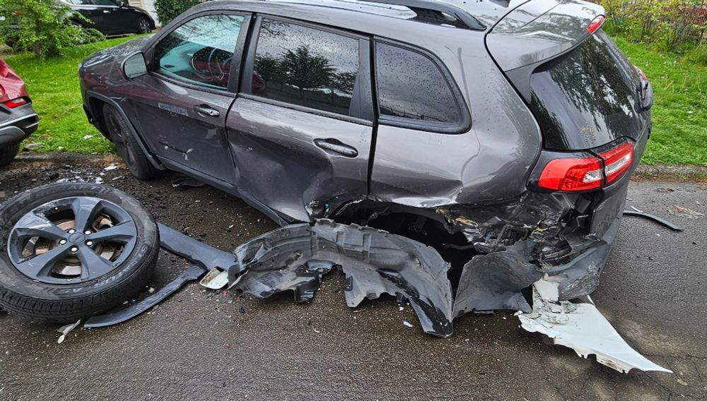 A photograph of a wrecked car with its rear tire torn off.