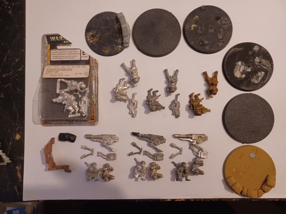 Photograph of all of the Armageddon Steel Legion heavy weapon teams we have available, including three complete Lascannon teams, one Heavy Bolter team still in the blister pack, one Heavy Bolter team only missing the bipod and two Heavy Bolter teams with the gun either missing or miscast. All teams have bases available.