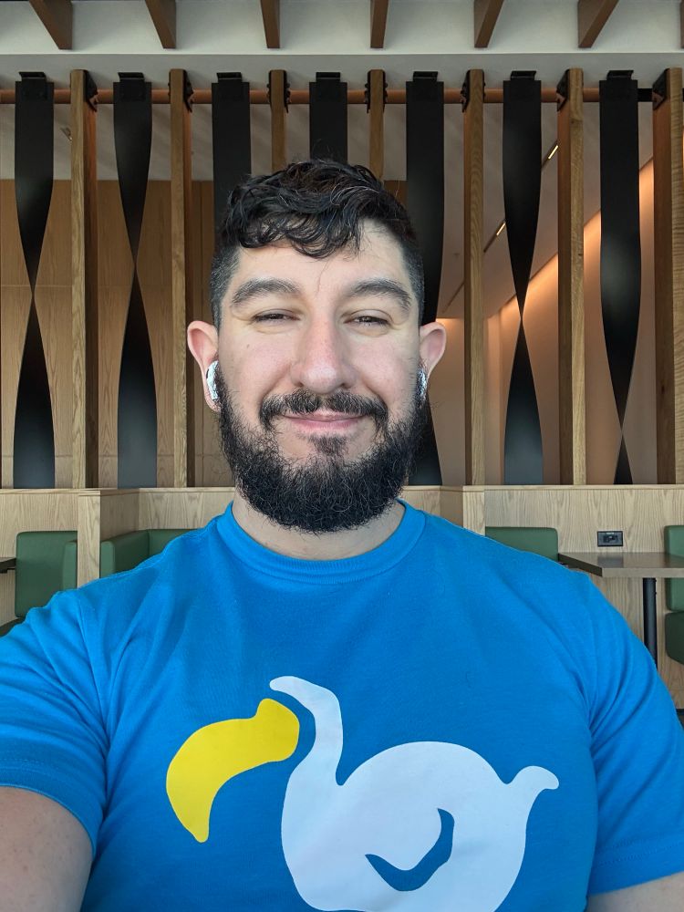 An image of myself wearing a blue shirt with a wire dodo screen printed on it, the logo for dodo airlines from the game animal crossing