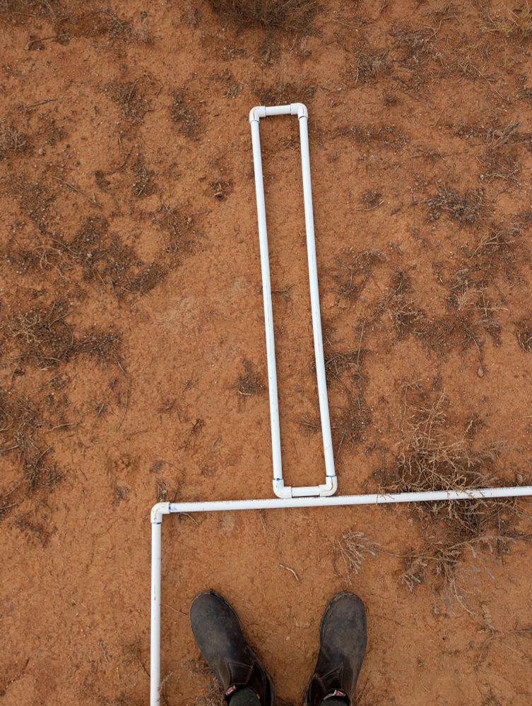 Two quadrats sit on bare red clay 