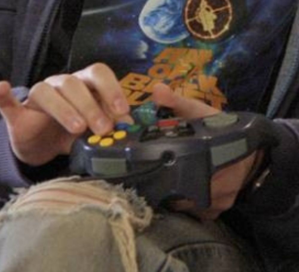 Closeup of Seth Rogan handling a (GameCube?) controller like he’s never held a controller in his life.