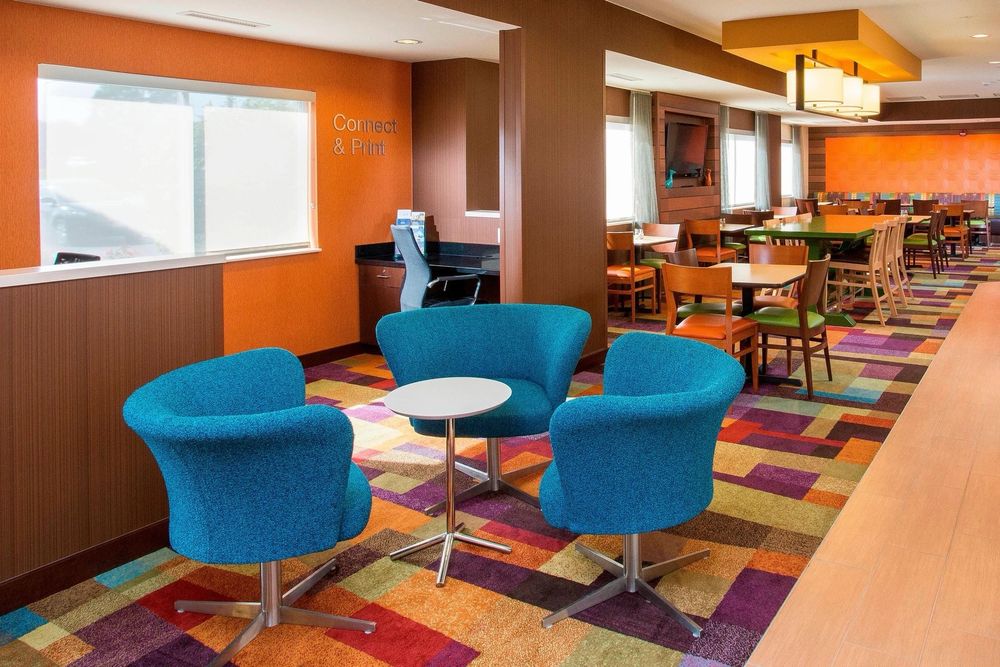 An uncomfortably vibrant orange hotel cafeteria with blue chairs and multicolored carpet.