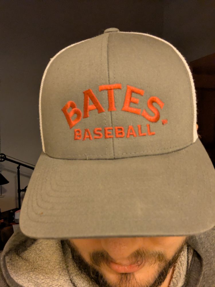 Grey trucker hat with white mesh that reads "Bates Baseball" in red embroidery 