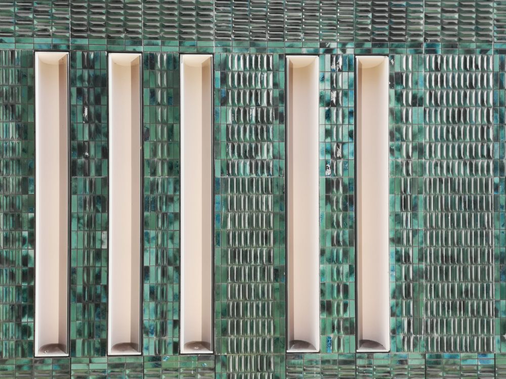 Green ceramic tiles with strong vertical concrete inclusions. Very abstract section of a shopping centre wall in Eindhoven