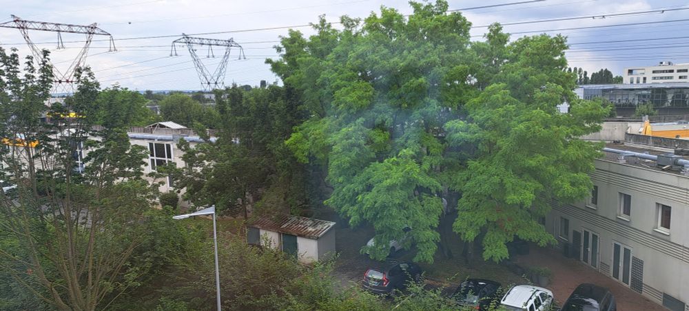 This is a photo of electricity pylons, a car park and trees taken from the window of a hotel in a suburb of Paris near Charles de Gaulle Airport