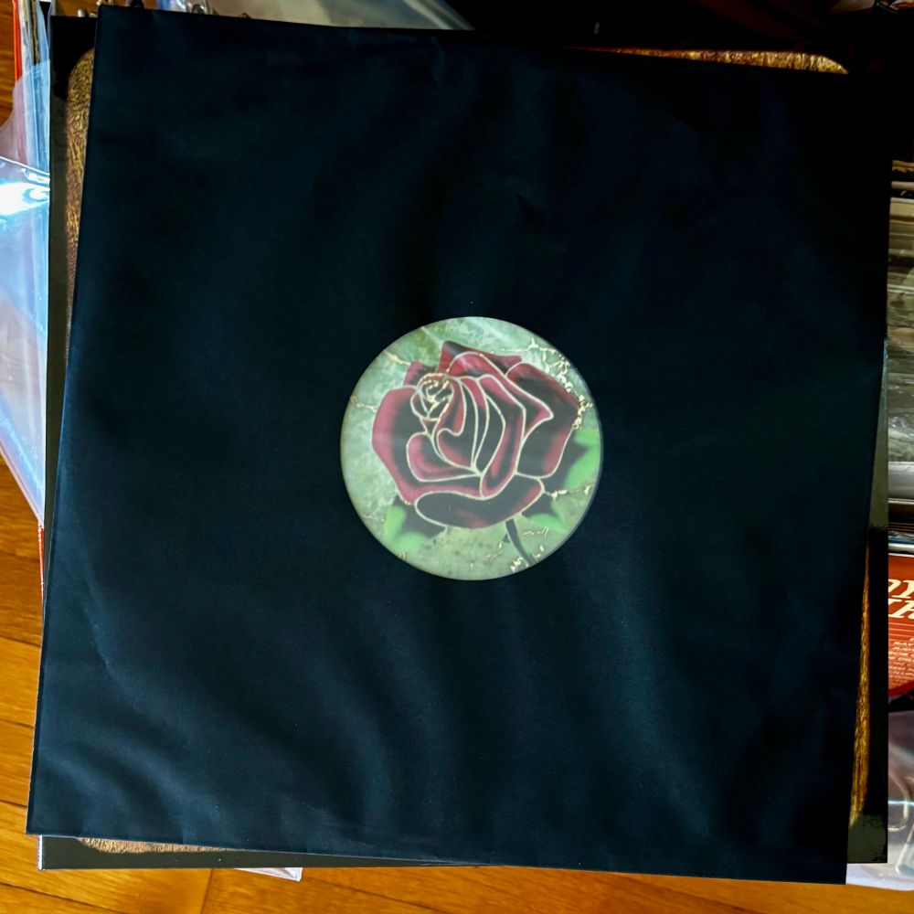 A black record sleeve with a circular window sits atop the LP jacket for Grateful Dead’s “American Beauty”. In the window is framed an illustration of a rose.

I’m in side two now and goddammit it, it’s fucking perfect.